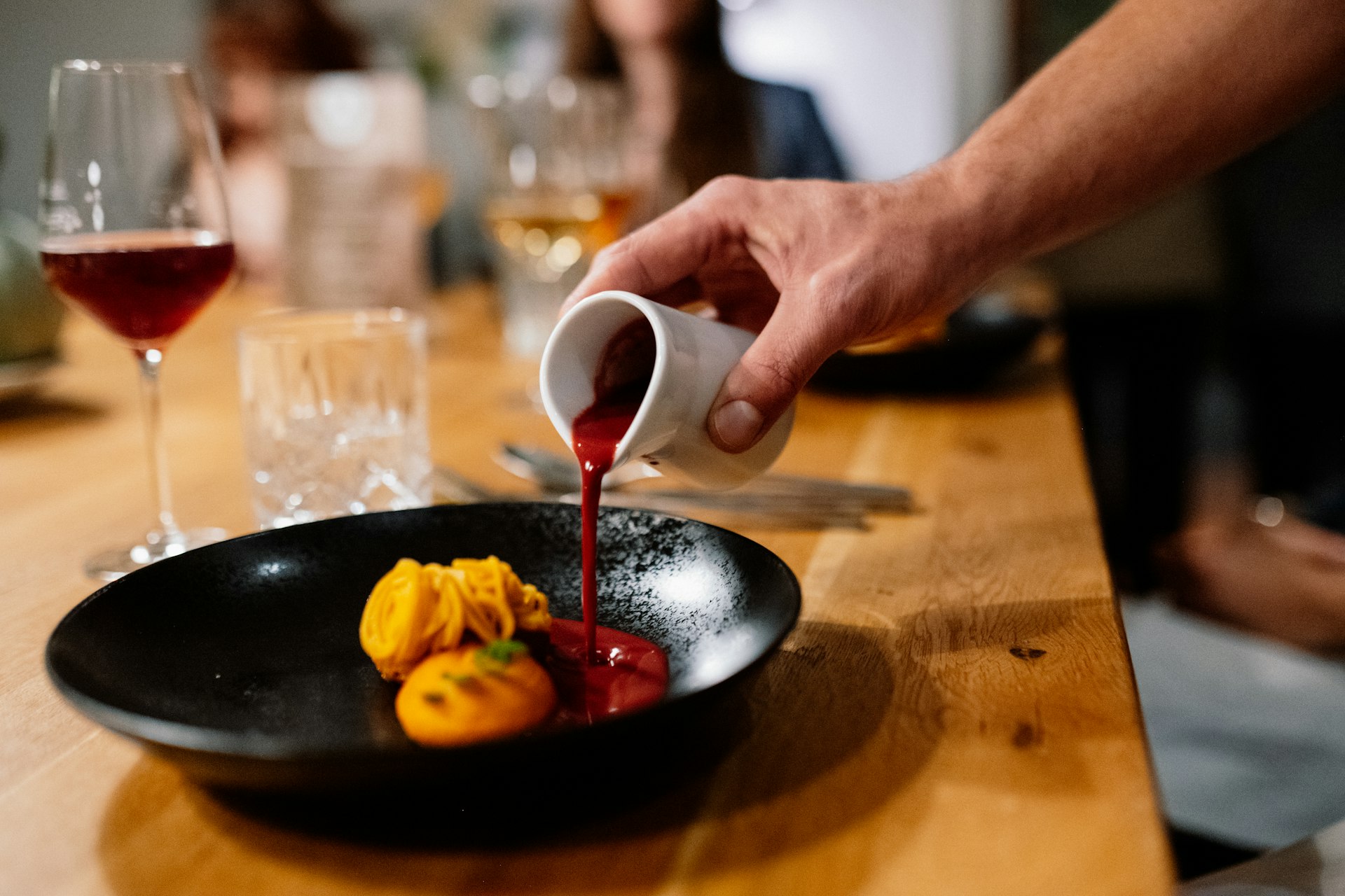 A person pouring sauce on a plate of food